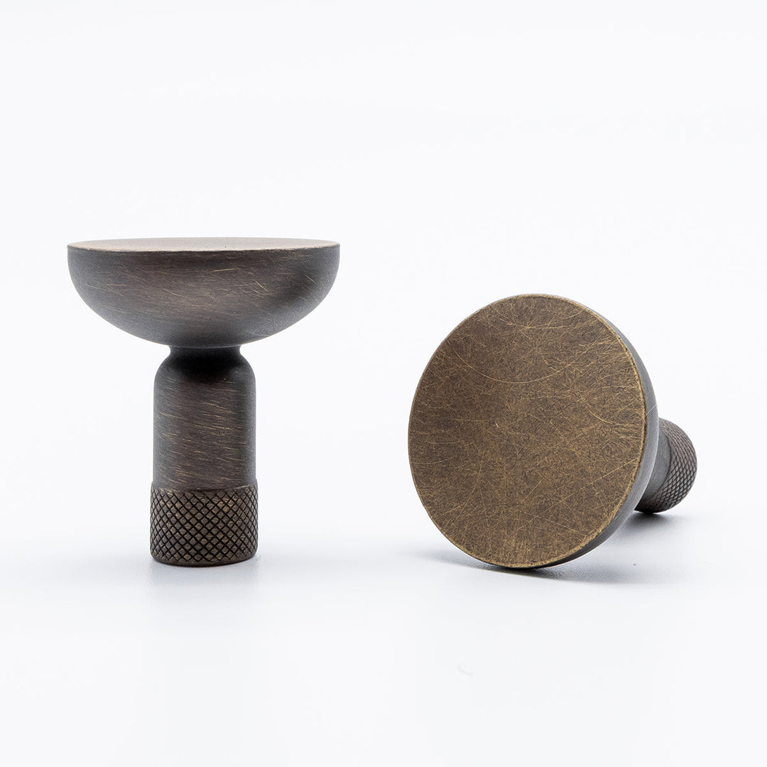 Two antique english finished brass cabinet knobs on a white background.