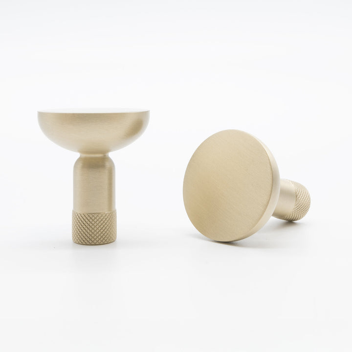 Two Hapny Knurled cabinet knobs in a satin brass finish, one standing and one angled lying down.
