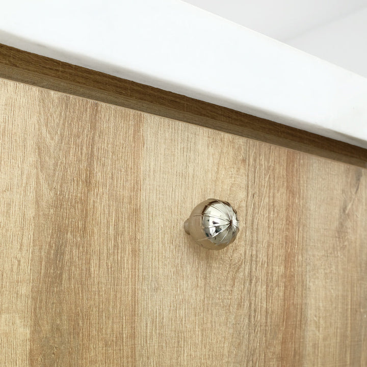 One Polished Nickel contemporary knob installed on a wooden cabinet door with a white marble countertop