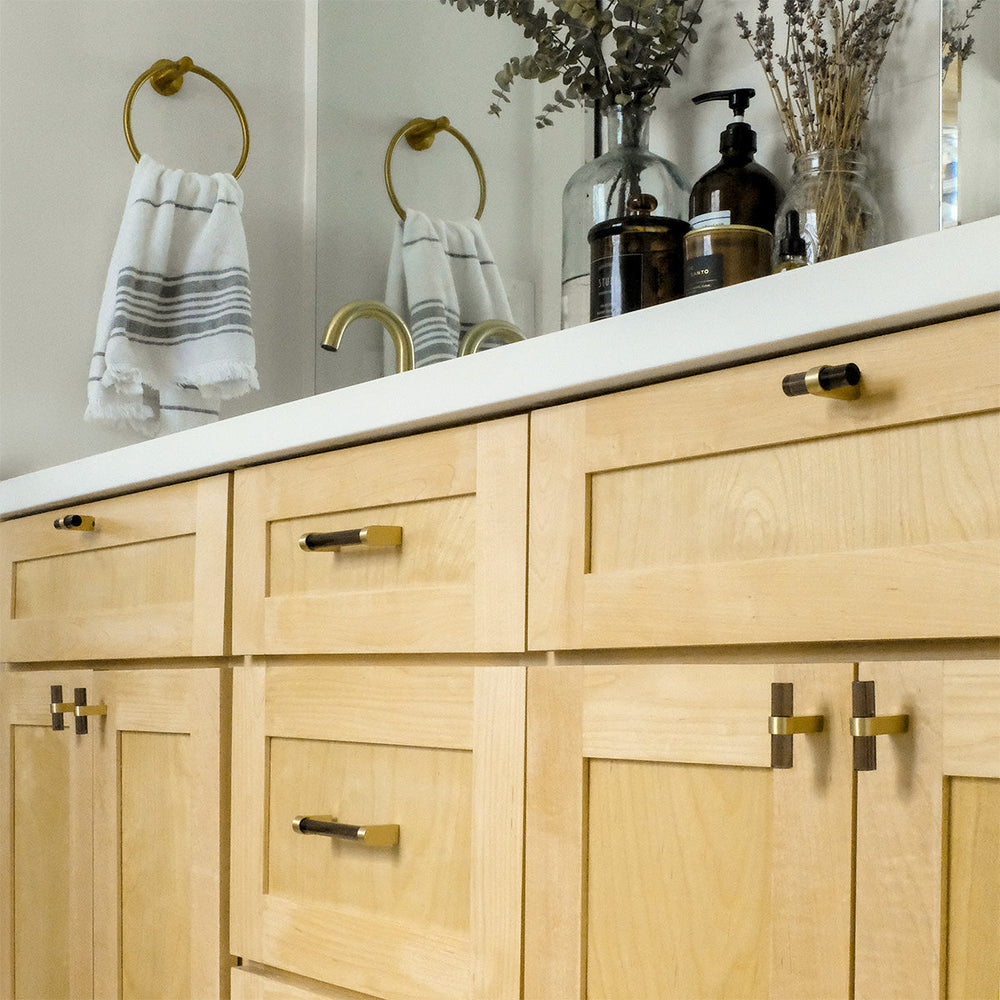 Wooden bathroom vanity with white countertop, gold and black fixtures, and decorative elements.