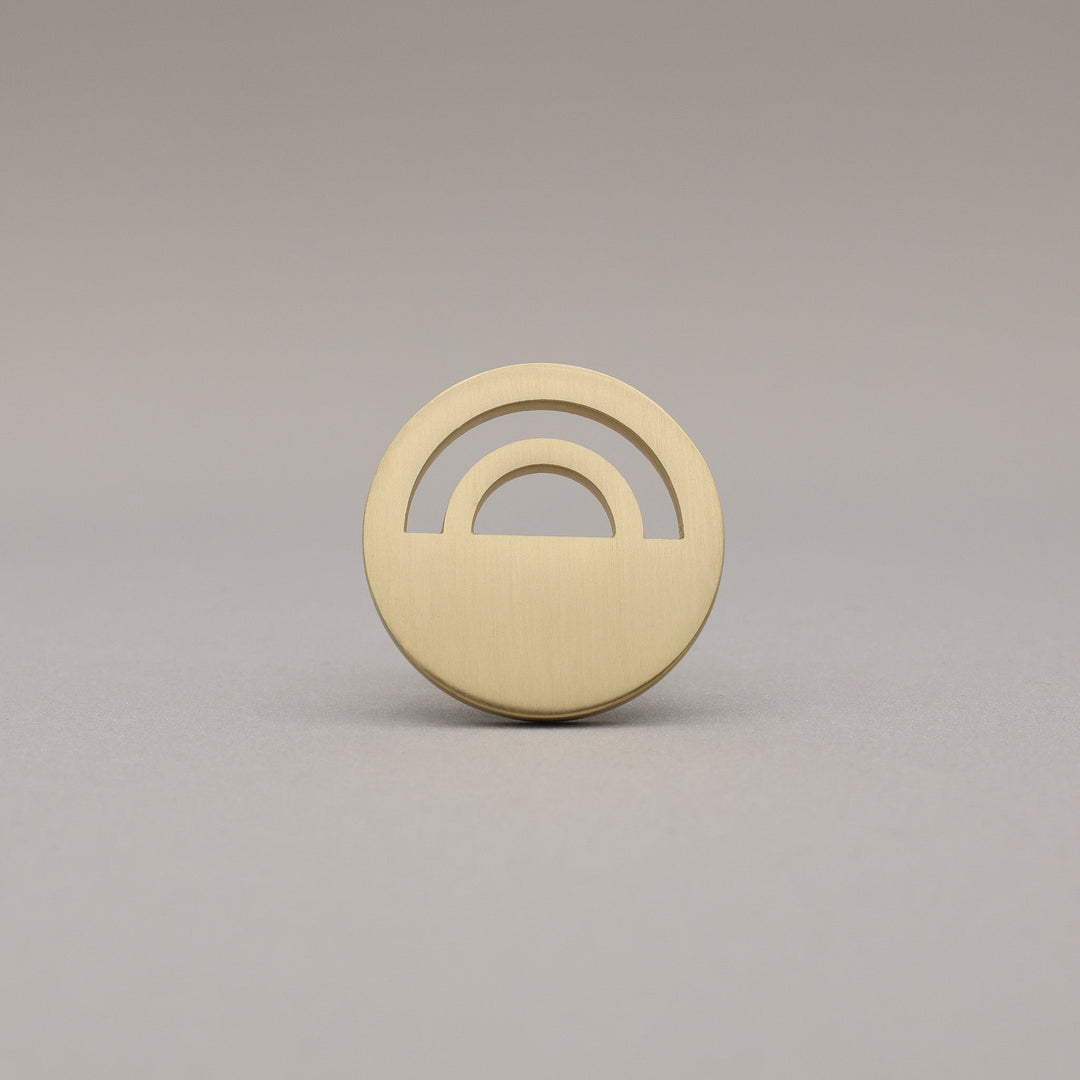 Horizon Satin Brass Knobs on grey background.
