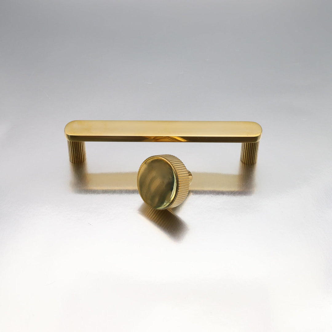 Unlacquered brass cabinet hardware with  on a light gray background.