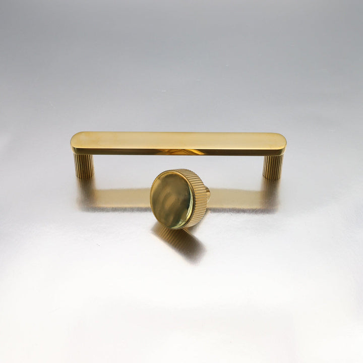 Unlacquered brass cabinet hardware with  on a light gray background.